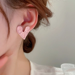 Close-up of pink heart-shaped earrings with unique wrinkled texture and glossy metallic finish