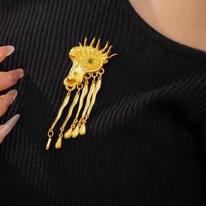 Detail view of a vintage surrealist eye brooch with long tassels on black knitwear