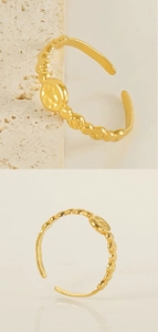 Détail d'une bague dorée ajustable avec médaillon gaufré et texture florale