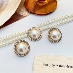 Détail de boucles d'oreilles et collier en perles dorées avec strass scintillants