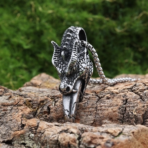 Gothic silver dragon head pendant necklace displayed on natural rustic tree bark