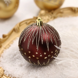 Boule de Noël bordeaux avec paillettes dorées sur un plateau décoratif enneigé