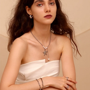 Close-up of silver starfish and pearl tassel pendant necklace on a model for detail