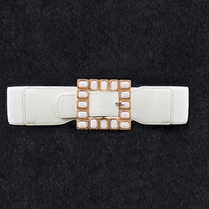 Detail of white elastic waist belt with gold square buckle and inset acrylic stones