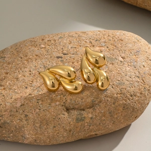 Macro detail of 18K gold plated stainless steel teardrop earrings on a natural stone