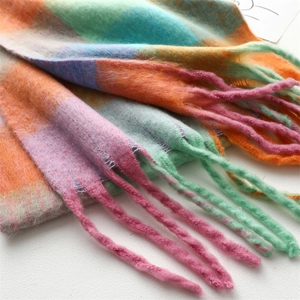 Detail of colorful rainbow grid scarf showing thick knit texture and long tassels