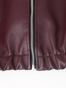 Detail of burgundy faux leather jacket featuring silver metal zipper and elastic hemline