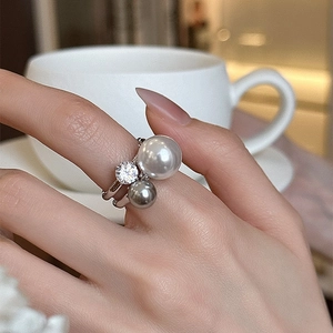 Detailed view of silver ring featuring white pearl, grey pearl, and zircon on model finger