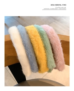Row of five colorful plush headbands in pastel colors displayed on a wooden chair