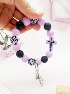 Close-up of leopard print silicone beads and a purple cross pendant engraved with Jesus