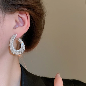 Close-up of elegant teardrop earrings with silver finish and pave-set zircons on model