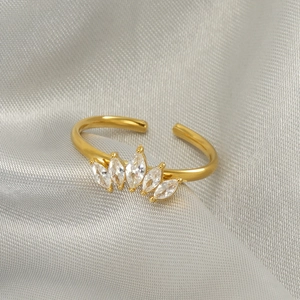 Detail shot of a gold crown ring with five marquise-cut zircons on gray silk fabric