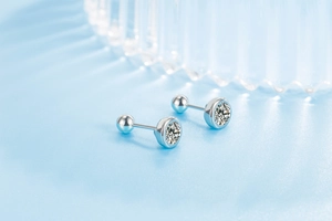 Macro detail of round zircon stud earring with secure screw back on light blue base