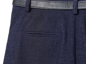 Dettaglio della chiusura in vita e tasca laterale su gonna a pieghe blu navy con cintura