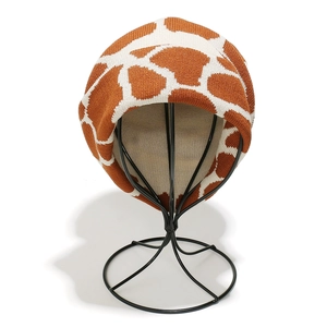 Detailed close-up of giraffe pattern knit texture on a winter beanie hat displayed on a stand