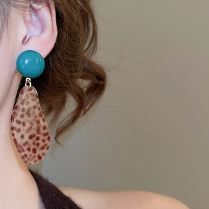 Close-up of leopard print resin drop earring with blue stud on model's ear