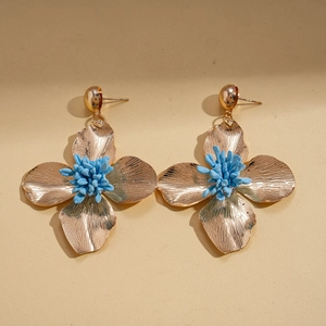 Close-up of vintage gold floral earrings with radial textures and blue textured centers