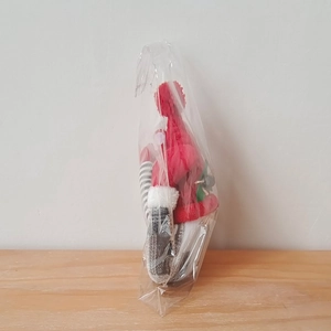 Macro d'une attache-rideau gnome de Noël dans un sac plastique avec un bonnet rouge tricoté