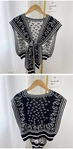 Detail of knit shawl featuring black and white paisley patterns with striped V-neck ties