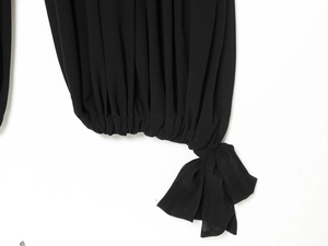 Détail d'une combinaison noire avec ourlet froncé et nœud élégant en ruban décoratif
