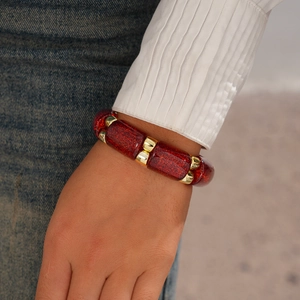 Detail of red glitter acrylic beads and gold metal spacers on an elastic bracelet