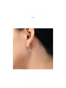 Detailed close-up of a silver safety pin earring worn on the earlobe with a sleek finish