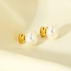 Macro shot of 16K gold plated stainless steel pearl earrings on soft silk fabric