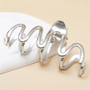 Sleek silver wavy metal hair claw clip with mirror finish on a minimalist display