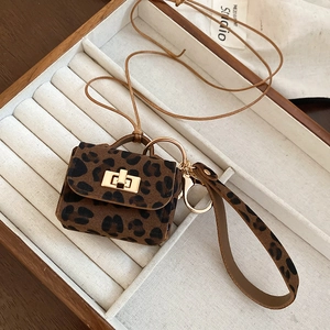 Macro detail of leopard print leather mini bag pendant with gold twist lock and metal ring