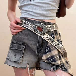 Close-up of vintage Y2K leather belt with heart-shaped rose metal buckle and red gemstone