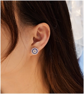 Close-up of model wearing round evil eye stud earrings with blue and white crystals