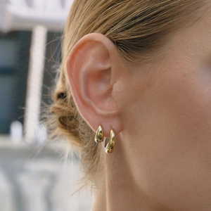 Details von klassischen gold- und silbernen Creolen am Ohr des Models