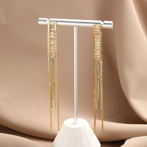 Macro detail of elegant gold-tone tassel earrings featuring crystal studs and long chains
