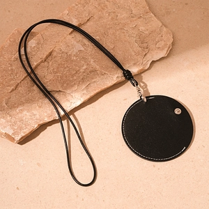 Detail of round black leather pendant necklace with silver clasp on a natural stone surface