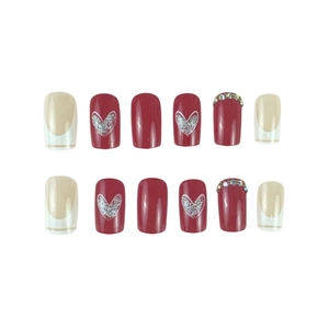Short French press-on nails set with red heart designs and rhinestone accents on white background