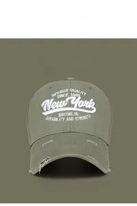 Close-up of olive green baseball cap with white 3D New York embroidery and distressed holes