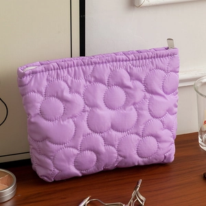 Dettaglio della borsa da trucco trapuntata viola con trama floreale e zip in argento