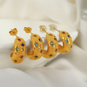 Vintage gold thick C-shaped earrings with colorful star-set rhinestones on fabric