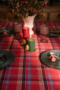 Tavola festiva con candele rosse e verdi su una tovaglia a quadri rossa e blu