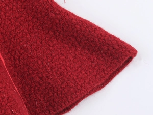 Dettaglio del tessuto a maglia rosso che mostra la texture in lana e l'orlo rifinito
