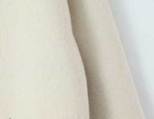 Close-up of beige knit fabric with soft brushed texture and detailed jacquard weave