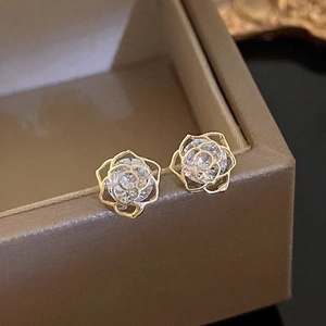 Elegant gold hollow rose stud earrings set with zircon stones on a jewelry box