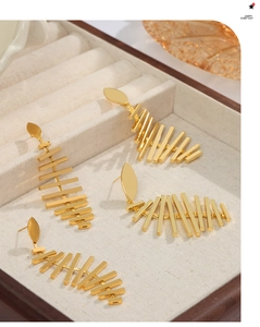 Detail of golden geometric layered earrings and fishbone tassels in a velvet jewelry box