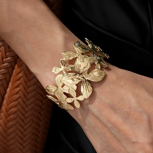 Detailed view of wide gold open cuff bracelet with intricate floral petal engravings