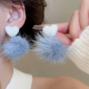 Primo piano di orecchini a cuore in tessuto con un morbido ciondolo a pompon in pelliccia