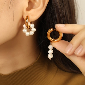 Boucles d'oreilles perles asymétriques vintage dorées portées par un mannequin élégant