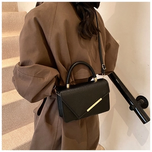 Detailed view of black litchi pattern leather bag with gold metal hardware and top handle