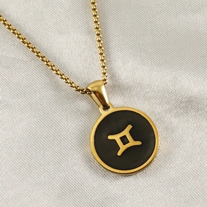 Close-up of 18K gold-plated Gemini constellation pendant with black enamel inlay details