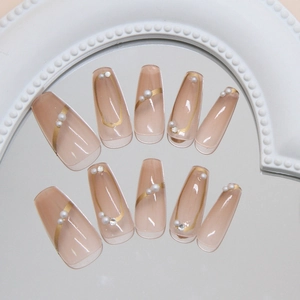 Faux ongles ballerine rose avec lignes dorées ondulées, perles blanches et strass brillants