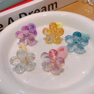 Close-up of five colorful crystal flower hair ties on a white ceramic tray detail